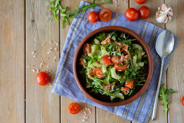 Vegetarian dish: Delicious salad of arugula, celery and cherry in a beautiful plate on a wooden table