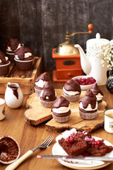 Chocolate cupcakes with cherries, cream and chocolate icing. Side view. Wooden background.