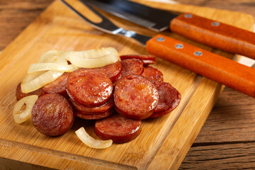Sliced ​​calabrese sausage with onion on wooden background.