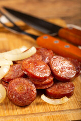 Sliced ​​calabrese sausage with onion on wooden background.