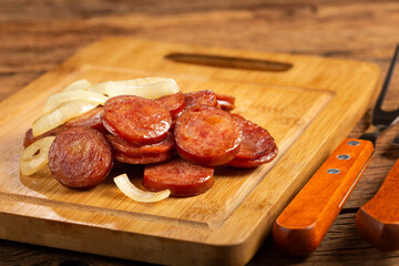 Sliced ​​calabrese sausage with onion on wooden background.