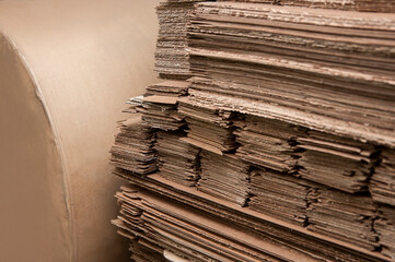 Sheets of corrugated cardboard and a large roll of offset paper in the warehouse of a printing...