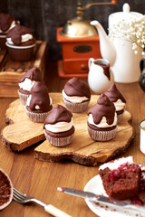 Chocolate cupcakes with cherries, cream and chocolate icing. Side view. Wooden background.