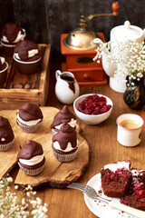Chocolate cupcakes with cherries, cream and chocolate icing. Side view. Wooden background.
