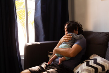 young happy hispanic father hugging and holding his newborn baby