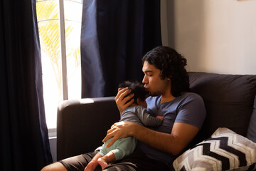 young happy hispanic father hugging and holding his newborn baby