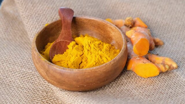 Turmeric Powder and roots, curcuma longa, kurkuma. panning turmeric on black background . top view. close up view. Slow motion video. stock footage
