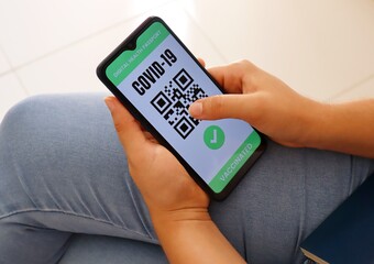 Vaccinated traveler holding Covid-19 Digital Health Passport app on smartphone screen for travel during Coronavirus pandemic.