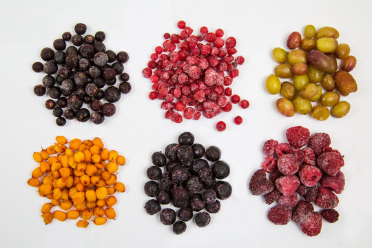 Berries of blueberries, red and black currants, sea buckthorn, raspberries, grapes, quick-frozen, laid out in small piles isolated on a white background, useful products vitamins.