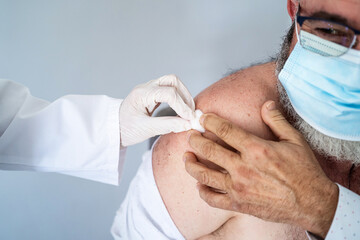 Elderly man with face mask recently vaccinated with the Covid-19 vaccine