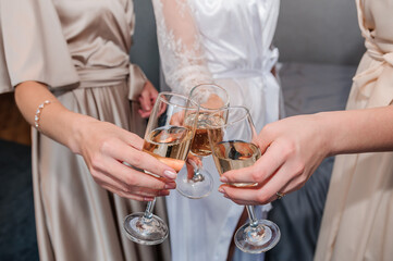 Glasses with white wine in the hands of the girls. Wine glasses in the hands of the bride and bridesmaids