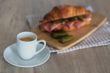 Coffee and croissant sandwich stuffed with salami and cornishons