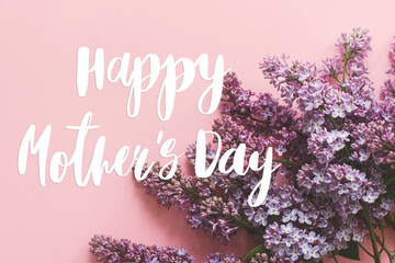 Fototapeta premium Happy mother's day. Happy mother's day text and lilac flowers on pink paper. Stylish floral greeting card. Handwritten lettering on purple lilac branch on pink. Mothers day