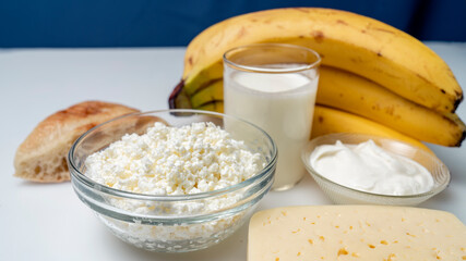 still life with banana and dairy products milk, bread and cheese on a white background