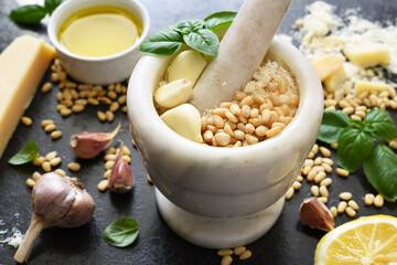 Ingredients for making pesto sauce: basil, parmesan, pine nuts in a marble mortar. Kitchen process.