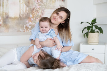 smiling mother with baby boy son and funny small preschooler daughter have fun at home