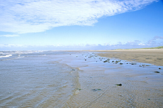 Empty beach and sea coast line in late afternoon light. blue and white clouds.