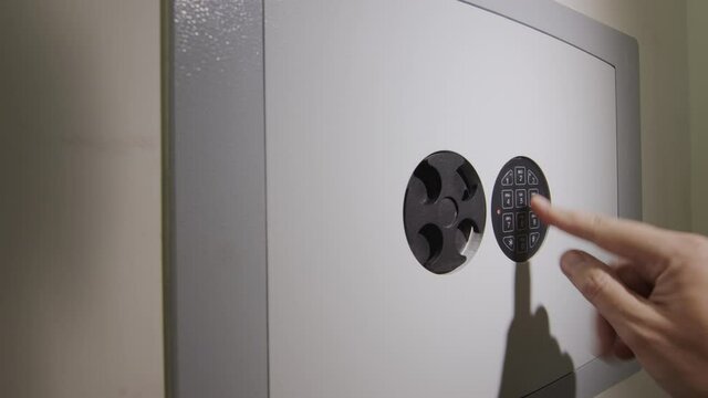 The man enters the password on the door of the safe and takes the gun from there