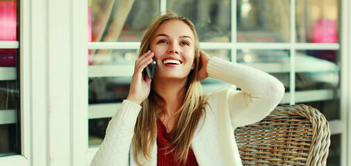 Portrait close up of happy smiling woman calling on a smartphone sitting at a table in cafe