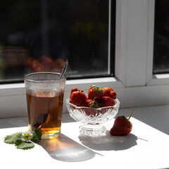 Cup of tea and wild strawberries on a wooden background