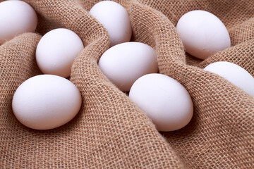 Bunch of white eggs on a brown rustic cloth.