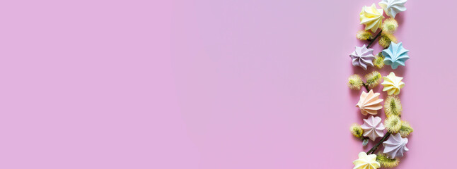 on a pink background, a spring composition of multi-colored gentle spring color meringue sweets and yellow fluffy spring twigs. copy space. banner