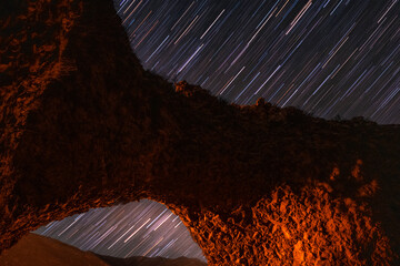 Beautiful night landscape. Arch in the cliff on the star trails sky backgroud. Starry summer night.