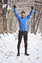 Happy man in winter sports outfit gesturing win in a park on a snowy day