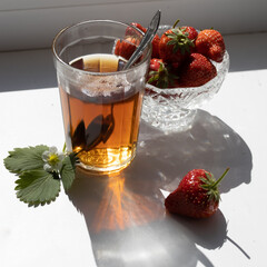 Cup of tea and wild strawberries on a white background
