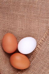 Three clean chicken eggs on a jute cloth.