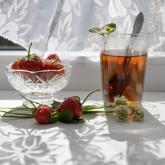 Cup of tea and wild strawberries on a white lace background