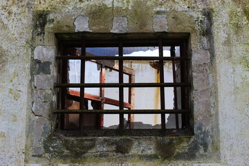 old window with bars on old wall