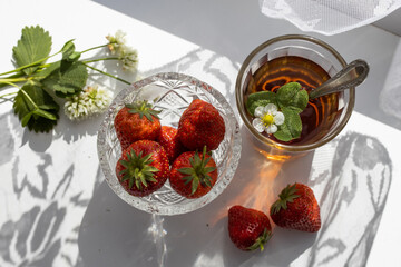 Cup of tea and wild strawberries on a white lace background