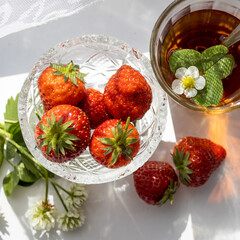 Cup of tea and wild strawberries on a white lace background
