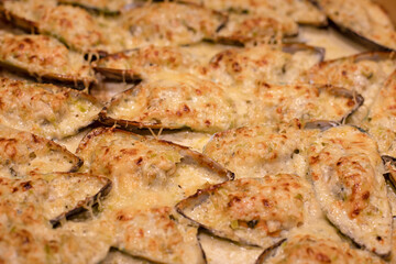 Concept food. Half of the mussels baked with cream sauce and cheese.