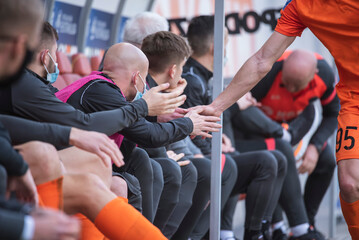 Football player gives five his college on the substitutes bench.