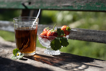 Cup of tea and wild strawberries on a wooden background