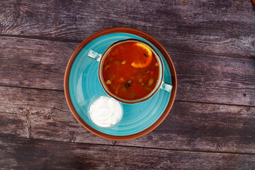 Traditional Ukrainian Russian borscht in a plate. A plate of red beet borscht on a dark table. Beetroot garden Top view.