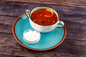Traditional Ukrainian Russian borscht in a plate. A plate of red beet borscht on a dark table. Beetroot garden Top view.