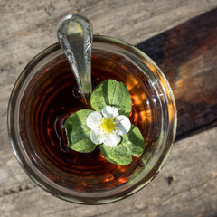 Cup of tea and wild strawberries on a wooden background