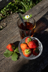 Cup of tea and wild strawberries on a wooden background