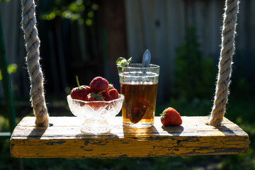 Cup of tea and wild strawberries on a wooden background