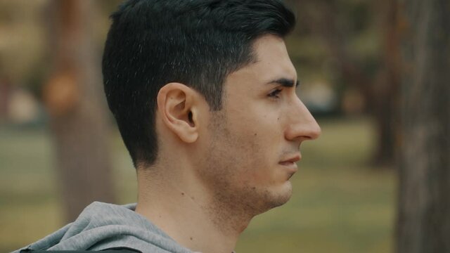 hombre pensativo e indeciso, cabeza de hombre de pelo negro de perfil, hombre preocupado con sudadera gris y luego da un paso adelante, cabeza hacia un lado