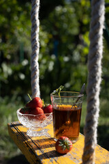 Cup of tea and wild strawberries on a wooden background