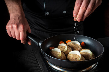 Cooking cutlets on grill pan by chef or cook hands on black background for copy space text restaurant menu. The chef adds salt