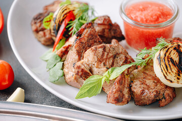 shish kebab and vegetables grilled and served on a white plate