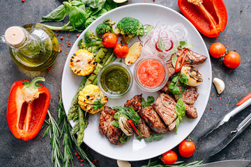 shish kebab and vegetables grilled and served on a white plate