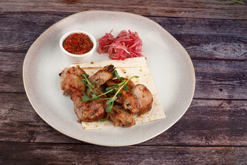Shish kebab on a plate. On a dark wooden table.