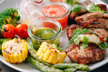shish kebab and vegetables grilled and served on a white plate