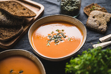 Vegetable creamy healthy soup with pumpkin seeds on a kitchen table.